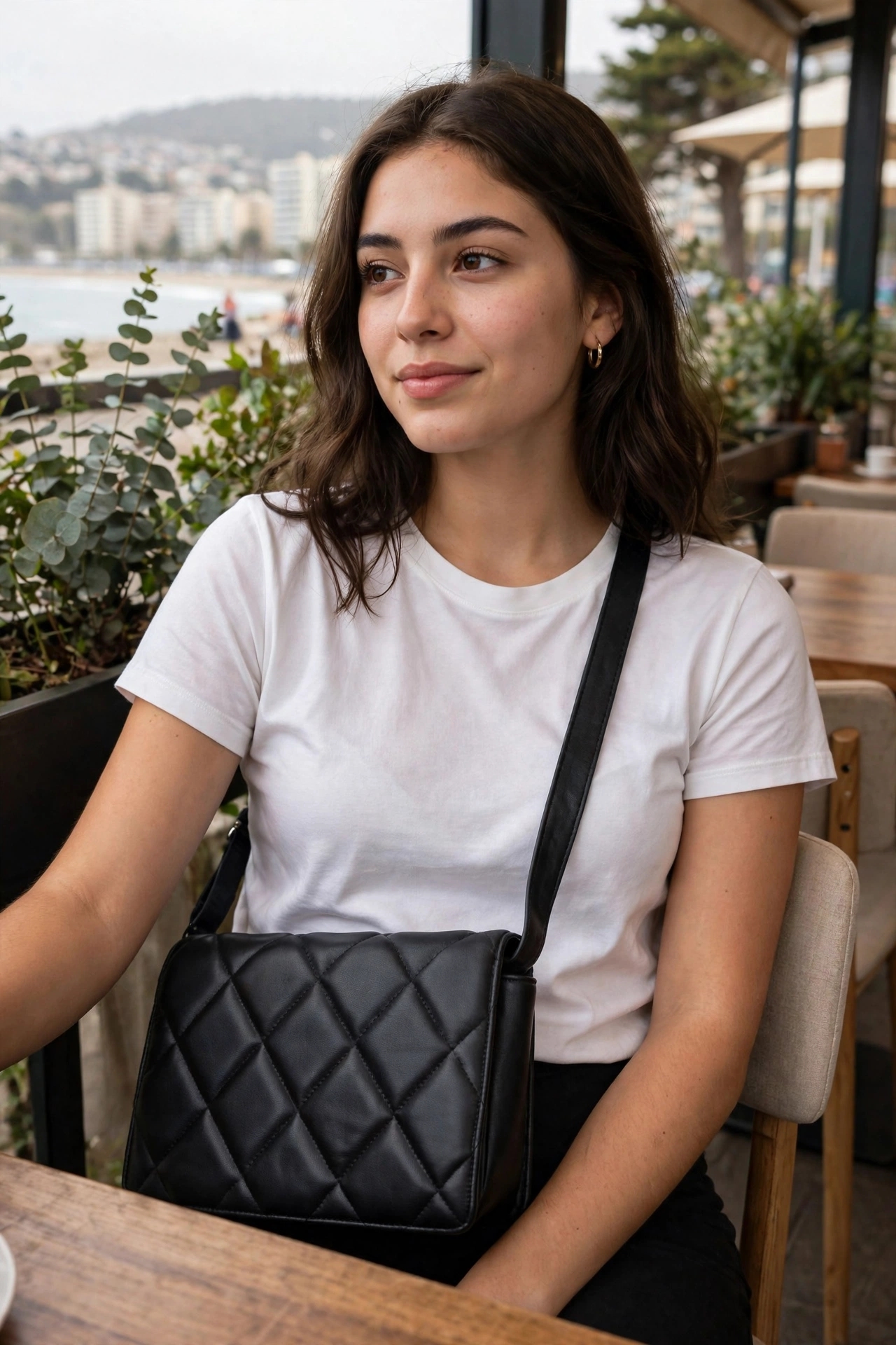 Bolso de hombro acolchado en color negro con diseño de rombos y correa ajustable